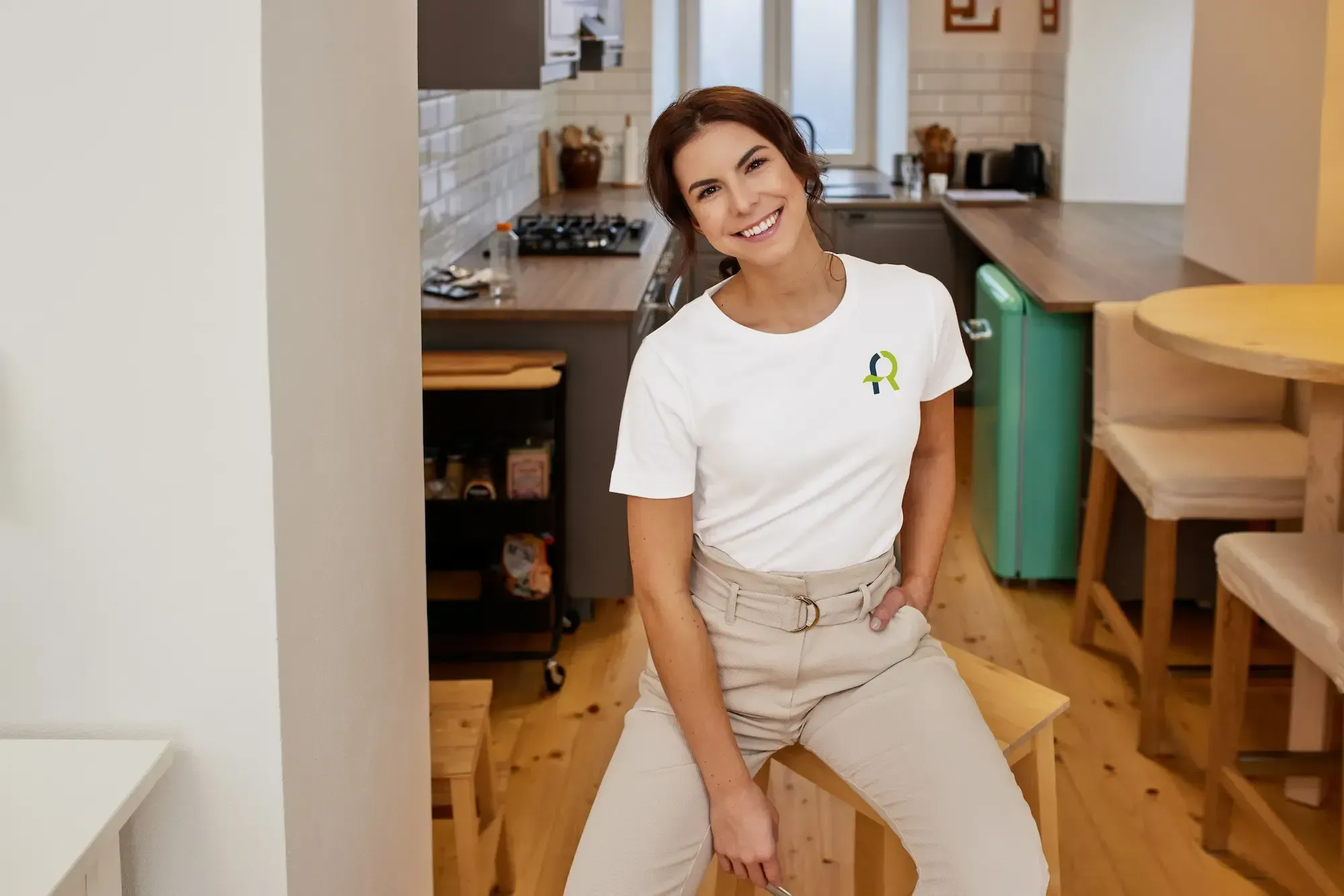 Persona sentada en una cocina moderna llevando una camiseta blanca con el logotipo de AFR Diseño & Impresión.
