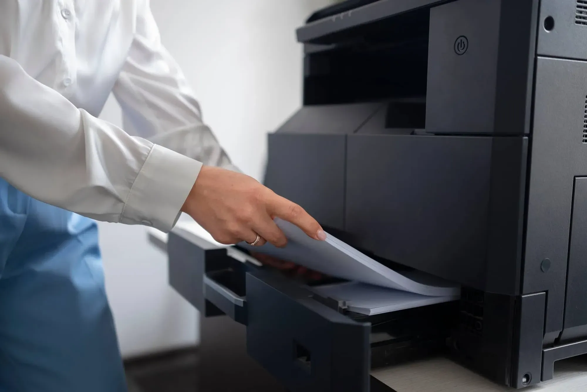 Persona cargando papel en una impresora.