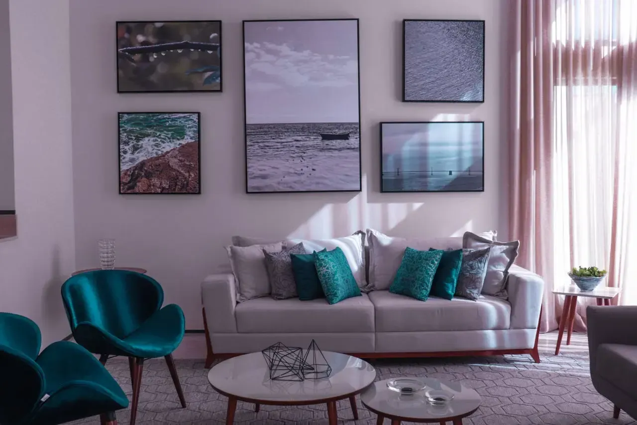 Composición decorativa con varias fotografías enmarcadas de paisajes marinos colgadas en la pared de un salón moderno.