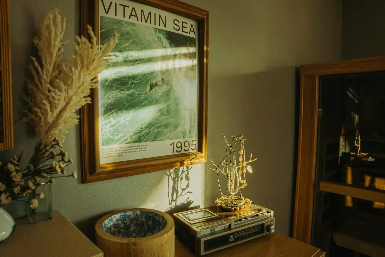 Póster decorativo enmarcado con una imagen aérea del mar y el texto “Vitamin Sea”, colocado sobre una mesa con objetos decorativos.