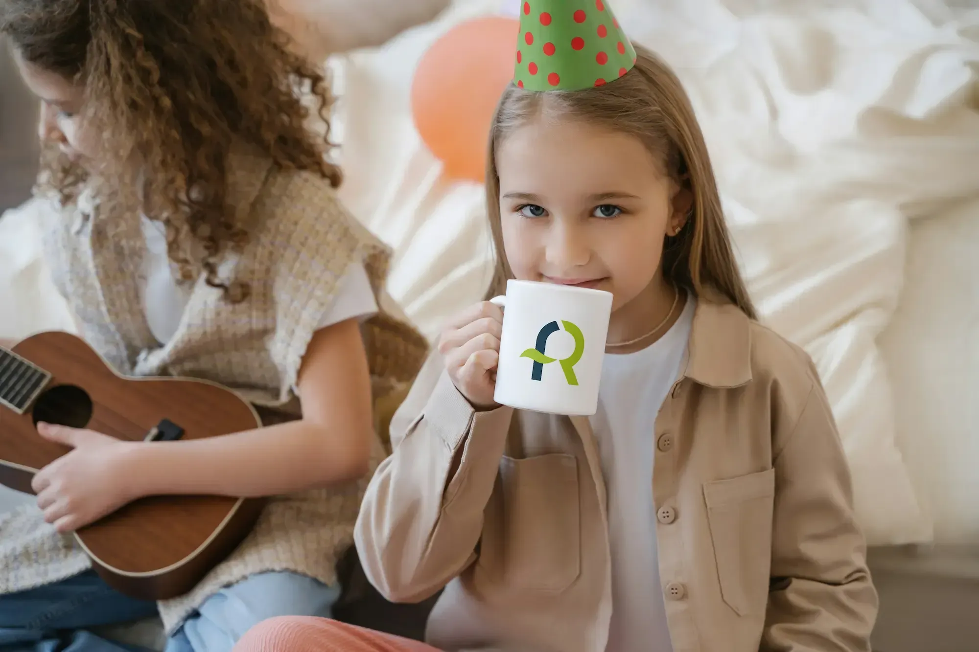 Niña sosteniendo una taza blanca con el logotipo de AFR Diseño & Impresión durante una celebración infantil.
